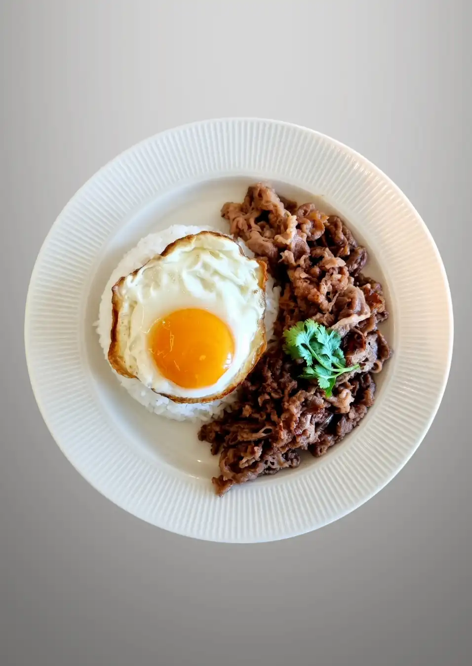 Savoury beef and rice topped with a fried egg, a single-plate Thai dish